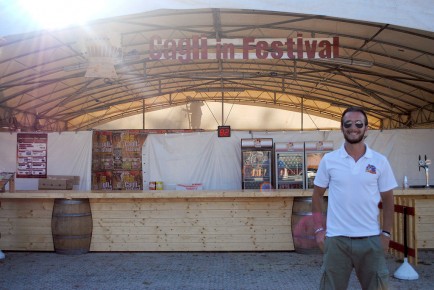 Director of the Festival in Cagli, Luca Ascani, stands in front of a beer kiosk.